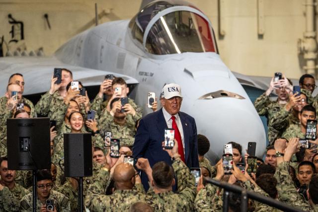 US Navy personnel use their mobile phones to take photos of US President Donald Trump as he arrives to deliver a speech on board the US Navy's USS George Washington aircraft carrier at the US naval base in Yokosuka on October 28, 2025. (Photo by Philip FONG / AFP)