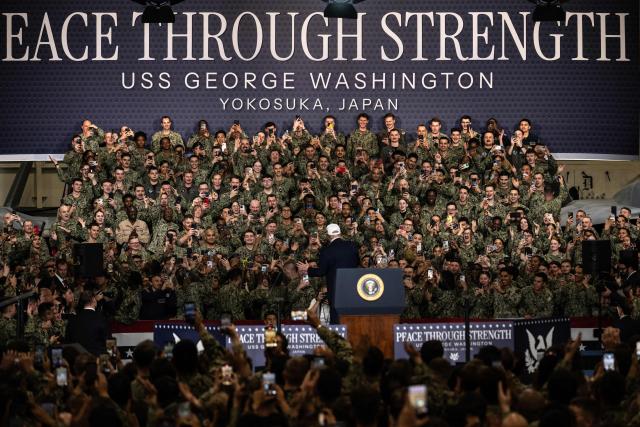 US Navy personnel use their mobile phones to take photos of US President Donald Trump as he arrives to deliver a speech on board the US Navy's USS George Washington aircraft carrier at the US naval base in Yokosuka on October 28, 2025. (Photo by Philip FONG / AFP)