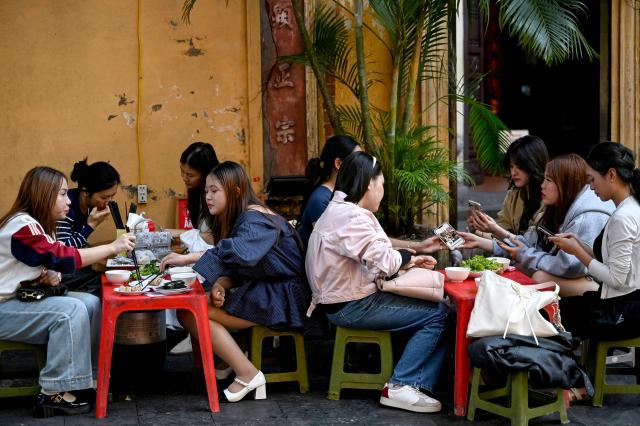 Women eat as they sit at a restaurant's terrace in Hanoi on October 28, 2025 (Photo by Nhac NGUYEN / AFP)