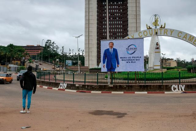 A pedestrian walks past a billboard of Cameroon's President Paul Biya reading: "I thank the sovereign people for electing me" on a street in Yaounde, on October 28, 2025 a day after the Cameroon presidential election results were announced. Cameroon's President Paul Biya, 92, has been re-elected for an eighth term with 53.7 percent of the vote, according to official results announced by the Constitutional Council on October 27, 2025. (Photo by AFP)