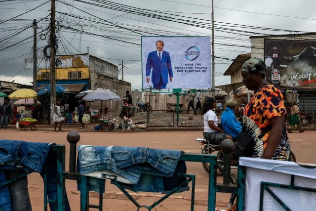 TOPSHOT - Pedestrians walk past a billboard of Cameroon's President Paul Biya reading: "I thank the sovereign people for electing me" on a street in Yaounde, on October 28, 2025 a day after the Cameroon presidential election results were announced. Cameroon's President Paul Biya, 92, has been re-elected for an eighth term with 53.7 percent of the vote, according to official results announced by the Constitutional Council on October 27, 2025. (Photo by AFP)