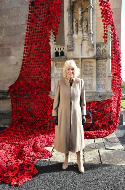 Britain's Queen Camilla reacts after attaching the final poppy to complete the cascade of 10,000 poppies draping the church tower, at St. Bartholomew's Church in Corsham, western England on October 28, 2025, as part of her visit to The Poppy Project. The The Poppy Project was launched by the Peacock Women's Institute (WI) at the start of the year, with a goal to create 10,000 poppies for display in the town. The group received over 31,000 poppies from across the UK and overseas, including schools, youth organisations, residential homes and businesses in the area. (Photo by Chris Jackson / POOL / AFP)