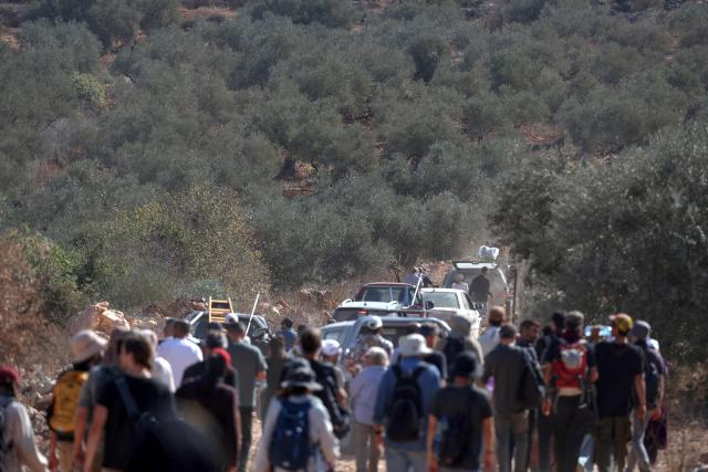 Palestinian farmers and foreign volunteers make their way to help harvest the olive groves near the Israeli occupied Palestinian West Bank village of Turmus Ayya, near the city of Ramallah on October 28, 2025. The Israeli army lobbed tear gas canisters at the farmers and volunteers to prevent them from picking the harvest. (Photo by Zain JAAFAR / AFP)