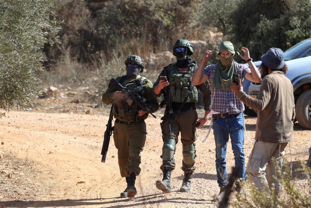 Israeli soldiers approach as Palestinian farmers and foreign volunteers try to harvest the olive near the Israeli occupied Palestinian West Bank village of Turmus Ayya, near the city of Ramallah on October 28, 2025. The Israeli army lobbed tear gas canisters at the farmers and volunteers to prevent them from picking the harvest. (Photo by Zain JAAFAR / AFP)