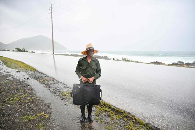 A resident of Playa Canizo waits for transport to evacuate to a safe location, ahead of the arrival of Hurricane Melissa, in Santiago de Cuba, Cuba, on October 28, 2025. Hurricane Melissa was set to strike nearby eastern end of Cuba late Tuesday after pummeling Jamaica. (Photo by YAMIL LAGE / AFP)
