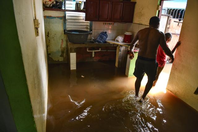 A couple leaves their flooded house ahead of the arrival of Hurricane Melissa at Las Cucarachas neighborhood in Santo Domingo, Dominican Republic on October 28, 2025. (Photo by Danny Polanco / AFP)