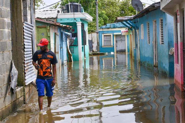 A couple leaves their flooded house ahead of the arrival of Hurricane Melissa at Las Cucarachas neighborhood in Santo Domingo, Dominican Republic on October 28, 2025. (Photo by Danny Polanco / AFP)