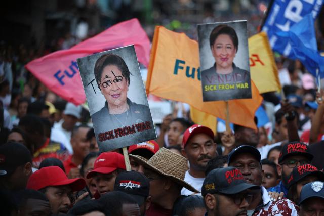 Supporters of venezuela's President Nicolas Maduro hold pictures of Trinidad and Tobago Prime Minister Kamla Persad-Bissessar during a rally against US and Trinidad and Tobago joint military exercises, in Caracas on October 28, 2025. (Photo by Pedro MATTEY / AFP)