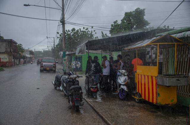 People take cover from the rain ahead of the arrival of Hurricane Melissa in Barahona, Dominican Republic on October 28, 2025. (Photo by Carlos FABAL / AFP)