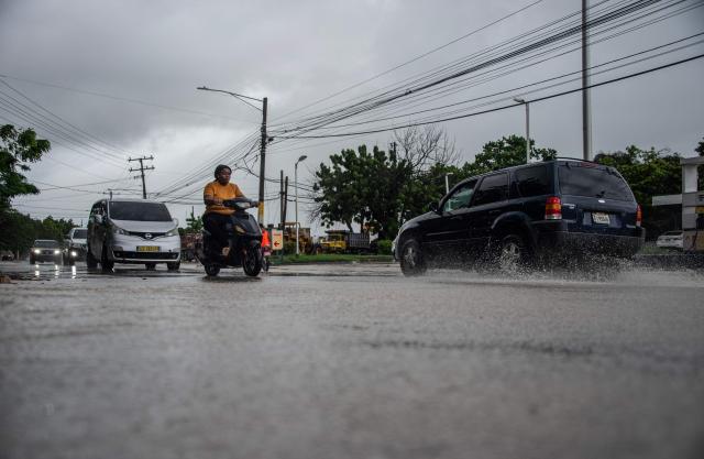 A man rides his motorbike under the rain ahead of the arrival of Hurricane Melissa in Barahona, Dominican Republic on October 28, 2025. (Photo by Carlos FABAL / AFP)