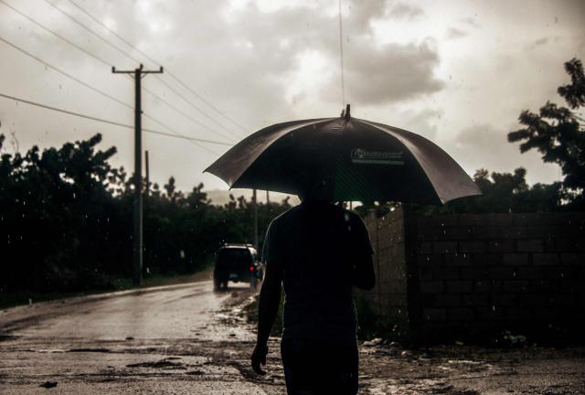 A man uses an umbrella ahead of the arrival of Hurricane Melissa in Barahona, Dominican Republic on October 28, 2025. (Photo by Carlos FABAL / AFP)