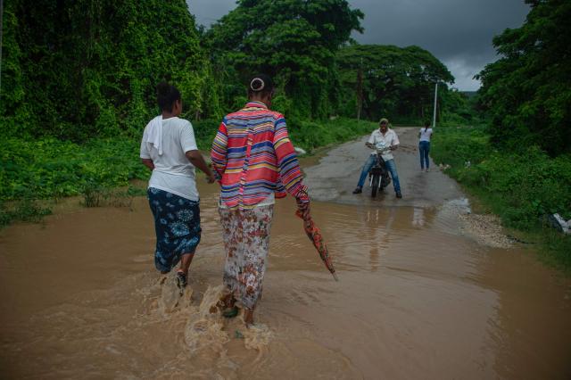 Women walks through flooded waters ahead of the arrival of Hurricane Melissa in Barahona, Dominican Republic on October 28, 2025. (Photo by Carlos FABAL / AFP)