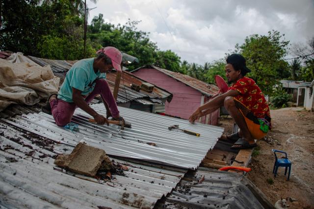 Two man fix the roof of a house ahead of the arrival of Hurricane Melissa in Barahona, Dominican Republic on October 28, 2025. (Photo by Carlos FABAL / AFP)