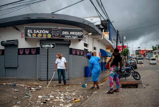 People clean a street ahead of the arrival of Hurricane Melissa in Barahona, Dominican Republic on October 28, 2025. (Photo by Carlos FABAL / AFP)
