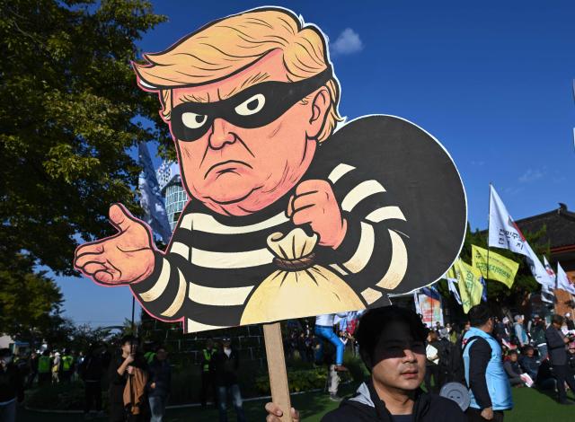 A South Korean protester holds a placard showing a caricature of Trump depicted as a thief during a rally against US President Trump's visit to attend the Asia-Pacific Economic Cooperation (APEC) Summit, in Gyeongju on October 29, 2025. (Photo by Jung Yeon-je / AFP)