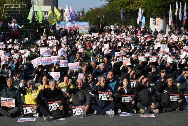South Korean protesters hold placards and shout slogans during a rally against US President Trump's visit to attend the Asia-Pacific Economic Cooperation (APEC) Summit, in Gyeongju on October 29, 2025. (Photo by Jung Yeon-je / AFP)