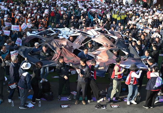 South Korean protesters tear a big banner showing a picture of Trump during a rally against US President Donald Trump's visit to attend the Asia-Pacific Economic Cooperation (APEC) Summit, in Gyeongju on October 29, 2025. (Photo by Jung Yeon-je / AFP)