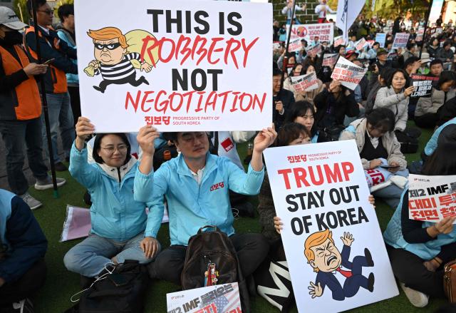 South Korean protesters hold placards during a rally against US President Donald Trump's visit to attend the Asia-Pacific Economic Cooperation (APEC) Summit, in Gyeongju on October 29, 2025. (Photo by Jung Yeon-je / AFP)