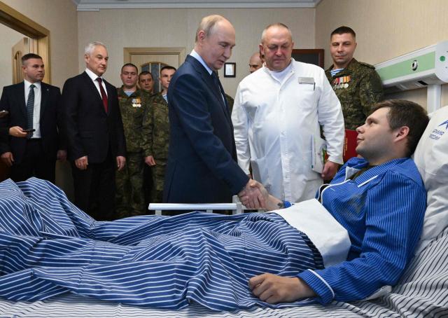 In this pool photograph distributed by the Russian state agency Sputnik, Russia's President Vladimir Putin (C) visits servicemen who were wounded during the Russian military action in Ukraine, at a military hospital in Moscow on October 29, 2025. (Photo by Kristina Kormilitsyna / POOL / AFP)