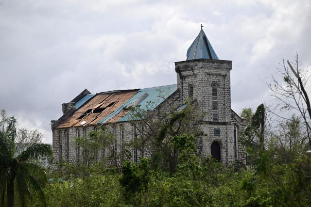 A Church with sections of its roof damage is seen damage following the passage of Hurricane Melissa, outside Santa Cruz, St Elizabeth, Jamaica on October 29, 2025. Hurricane Melissa ripped up trees and knocked out power after making landfall in Jamaica on October 28, 2025 as one of the most powerful hurricanes on record, inundating the island nation with rains that threaten flash floods and landslides. (Photo by Ricardo MAKYN / AFP)
