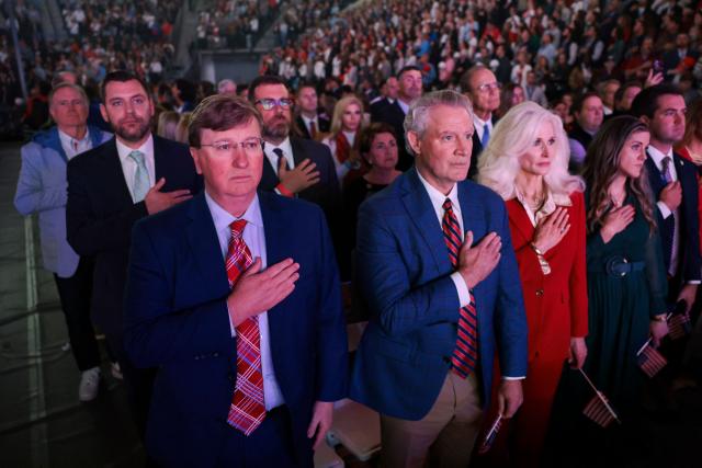 Governor of Mississippi, Tate Reeves (L), stands with other attendees during the national anthem during a Turning Point USA where US Vice President JD Vance is expected, at the University of Mississippi, in Oxford, Mississippi, October 29, 2025. (Photo by JONATHAN ERNST / POOL / AFP)