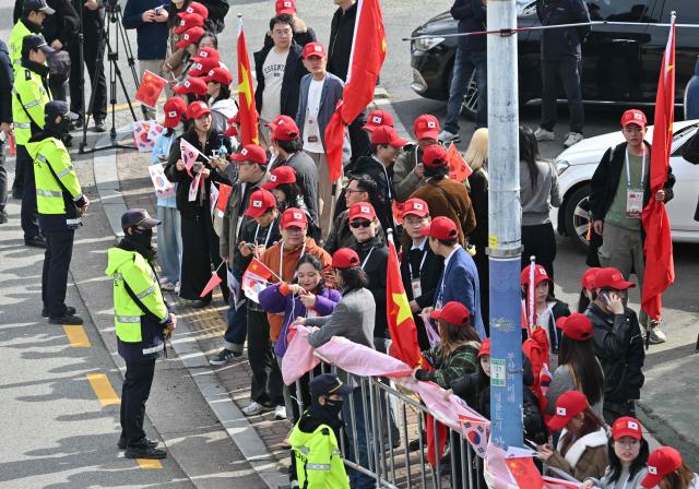 Chinese people gather to welcome their president outside a gate of an air base at Gimhae International Airport in Busan on October 30, 2025, as Chinese President Xi Jinping arrives to attend the Asia-Pacific Economic Cooperation (APEC) Summit. (Photo by Jung Yeon-je / AFP)