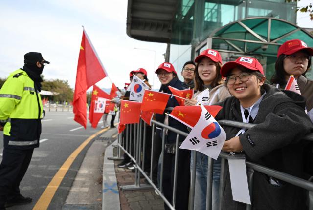 Chinese people gather to welcome their president outside a gate of an air base at Gimhae International Airport in Busan on October 30, 2025, as Chinese President Xi Jinping arrives to attend the Asia-Pacific Economic Cooperation (APEC) Summit. (Photo by Jung Yeon-je / AFP)