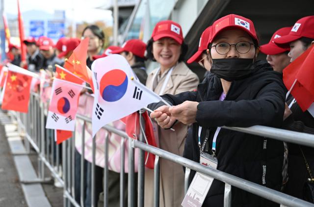 Chinese people gather to welcome their president outside a gate of an air base at Gimhae International Airport in Busan on October 30, 2025, as Chinese President Xi Jinping arrives to attend the Asia-Pacific Economic Cooperation (APEC) Summit. (Photo by Jung Yeon-je / AFP)