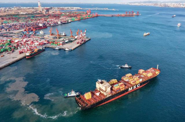 An aerial view shows tugboats alongside a cargo ship at the port in Qingdao, in China’s eastern Shandong province on October on October 29, 2025. (Photo by AFP) / China OUT