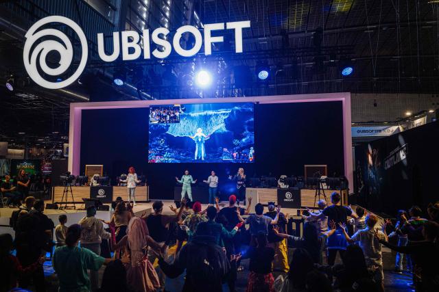 (FILES) Visitors dance at the Ubisoft stand during the Paris Games Week fair in Paris, on October 23, 2024. The 14th edition of the Paris Games Week, the most significant event in the sector in France, returns on October 30, 2025, to the Porte de Versailles in a new format, celebrating an industry regaining its confidence. (Photo by Dimitar DILKOFF / AFP)