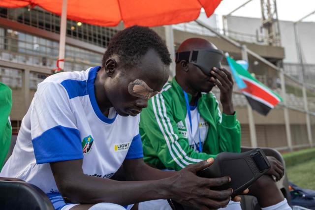 Players from South Sudans blind football team react on the bench during a match against Uganda at Hamz Stadium Nakivubo War Memorial Grounds in Kampala, on October 27, 2025. South Sudan's national blind football team, the Bright Stars, is making its international debut in a mini-tournament in Kampala, featuring teams from Uganda and Zimbabwe. The tournament offers the team greater visibility and a chance to compete for a spot at the 2028 Paralympics in California. South Sudan's team began humbly five years ago with just two players under the guidance of sighted head coach Simon Madol Akol, who has since grown the team to 40 members. (Photo by Stuart Tibaweswa / AFP)