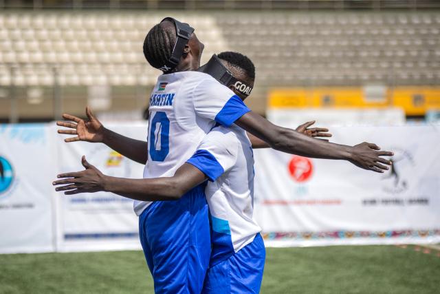 Martin Ladu Paul, 23, team captain of South Sudans blind football team, (L) celebrates with a teammate after scoring a goal during their match against Uganda at Hamz Stadium Nakivubo War Memorial Grounds in Kampala, on October 27, 2025. South Sudan's national blind football team, the Bright Stars, is making its international debut in a mini-tournament in Kampala, featuring teams from Uganda and Zimbabwe. The tournament offers the team greater visibility and a chance to compete for a spot at the 2028 Paralympics in California. South Sudan's team began humbly five years ago with just two players under the guidance of sighted head coach Simon Madol Akol, who has since grown the team to 40 members. (Photo by Stuart Tibaweswa / AFP)