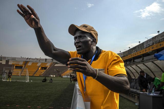 Simon Madol Akol, head coach of South Sudans blind football team, directs his team from the sidelines during their match against Uganda at Hamz Stadium Nakivubo War Memorial Grounds in Kampala, on October 27, 2025. South Sudan's national blind football team, the Bright Stars, is making its international debut in a mini-tournament in Kampala, featuring teams from Uganda and Zimbabwe. The tournament offers the team greater visibility and a chance to compete for a spot at the 2028 Paralympics in California. South Sudan's team began humbly five years ago with just two players under the guidance of sighted head coach Simon Madol Akol, who has since grown the team to 40 members. (Photo by Stuart Tibaweswa / AFP)