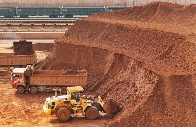 Heavy machinery handling bauxite ore is seen at the Yantai port in eastern China's Shandong province on October 29, 2025. (Photo by AFP) / China OUT