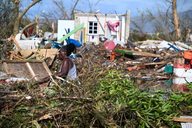 A woman is seen next to a damaged building following the passage of Hurricane Melissa, in Black River, St. Elizabeth, Jamaica on October 29, 2025. Hurricane Melissa bore down on the Bahamas October 29 after cutting a path of destruction through the Caribbean, leaving 30 people dead or missing in Haiti and parts of Jamaica and Cuba in ruins. 
Somewhat weakened but still threatening, Melissa will bring damaging winds and flooding rains to the Bahamas Wednesday before moving on to Bermuda late Thursday, according to the US National Hurricane Center (NHC). (Photo by Ricardo Makyn / AFP)