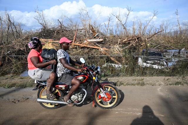 Residents drive past debris littering the side of the road following the passage of Hurricane Melissa, in Black River, St. Elizabeth, Jamaica on October 29, 2025. Hurricane Melissa bore down on the Bahamas October 29 after cutting a path of destruction through the Caribbean, leaving 30 people dead or missing in Haiti and parts of Jamaica and Cuba in ruins. 
Somewhat weakened but still threatening, Melissa will bring damaging winds and flooding rains to the Bahamas Wednesday before moving on to Bermuda late Thursday, according to the US National Hurricane Center (NHC). (Photo by Ricardo Makyn / AFP)