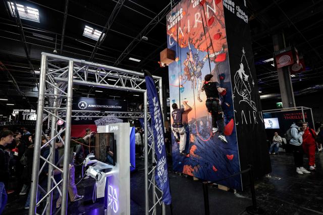 Visitors take part video game linked to a climbing wall during the Paris Games Week fair in Paris, on October 30, 2025. Supported by new partners, the 14th edition of the largest video game fair in France is making its return until November 2, 2025 at the Porte de Versailles in Paris, in a format even more focused on shows and pop culture. (Photo by STEPHANE DE SAKUTIN / AFP)