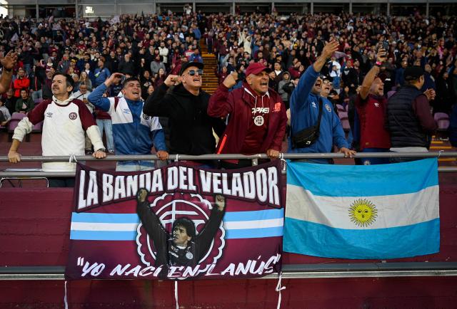 Lanus fans display a banner depicting late Argentine football legend Diego Maradona in honor of his birthday during the Copa Sudamericana semifinal second leg football match between Argentina's Lanus and Chile's Universidad de Chile at the Ciudad de Lanus stadium in Lanus, Buenos Aires province, on October 30, 2025. (Photo by Luis ROBAYO / AFP)
