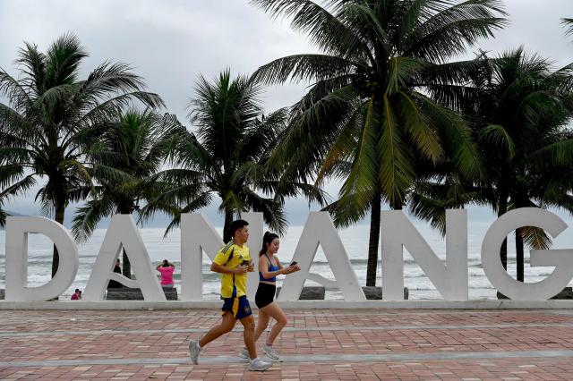 A couple runs along the seafront next to the beach in Da Nang in central Vietnam on October 31, 2025. (Photo by Nhac NGUYEN / AFP)