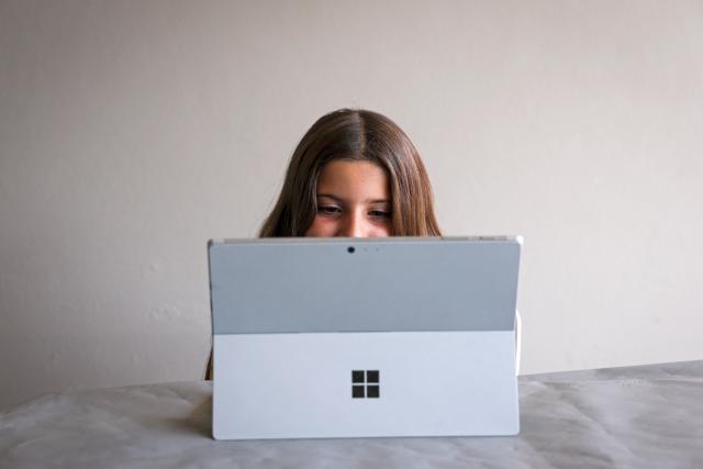 This photo taken on October 30, 2025 shows 10-year-old Bianca Navarro reacting as she watches a show on YouTube at her home in western Sydney. Tech giants Meta and TikTok said on October 28 they will obey Australia's under-16 social media ban but warned the landmark laws could prove difficult to enforce. Australia will from December 10 force social media platforms such as Facebook, Instagram and TikTok to remove users under the age of 16. (Photo by David GRAY / AFP)