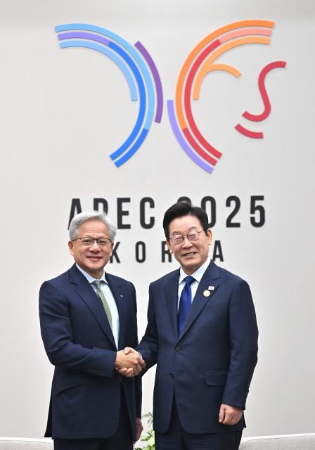 South Korean President Lee Jae Myung (R) shakes hands with Nvidia founder and CEO Jensen Huang (L) during their meeting on the sidelines of the Asia-Pacific Economic Cooperation (APEC) summit in Gyeongju on October 31, 2025. (Photo by JUNG YEON-JE / POOL / AFP)