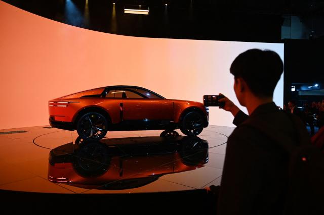 A man takes photos of a Century Coupe at the Japan Mobility Show in Tokyo on October 31, 2025. (Photo by GREG BAKER / AFP)