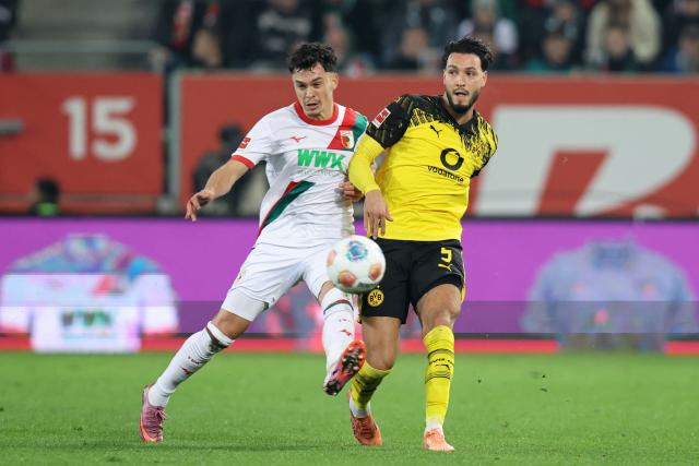 Augsburg's German midfielder #30 Anton Kade (L) and Dortmund's Algerian defender #05 Ramy Bensebaini vie for the ball during the German first division Bundesliga football match between FC Augsburg and Borussia Dortmund in Augsburg, southern Germany on October 31, 2025. (Photo by Alexandra BEIER / AFP) / DFL REGULATIONS PROHIBIT ANY USE OF PHOTOGRAPHS AS IMAGE SEQUENCES AND/OR QUASI-VIDEO
