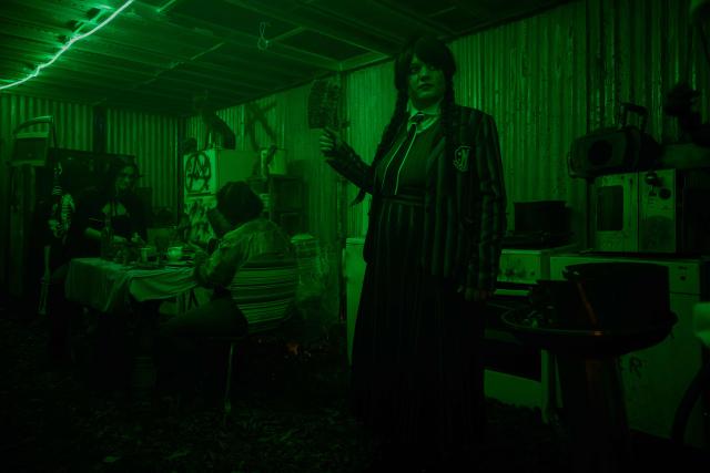 A performer dressed in a "Wednesday Addams" inspired costume stands in one of the rooms of the volunteer-run haunted house attraction featuring horror-themed decorations for Halloween in Ambes, on the outskirts of Bordeaux, south-western France, on October 31, 2025. The seasonal horror attraction, which opens exclusively on Halloween, marks its 10th anniversary this year with an expanded venue after creator Antoine Vignaud took a year off to prepare this special edition. (Photo by Philippe LOPEZ / AFP)