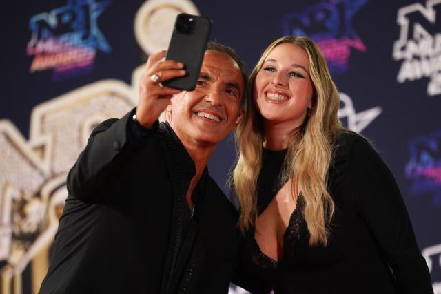 French TV host Nikos Aliagas and Belgian singer and Former Star Academy participant Helena Bailly pose upon arrival on the red carpet to attend the 27th edition of the NRJ Music Awards ceremony at the Palais des Festivals, in Cannes, southeastern France, on October 31, 2025. (Photo by Valery HACHE / AFP)