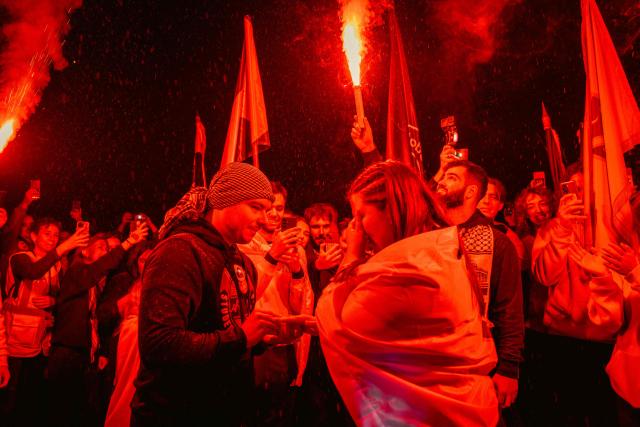 A woman reacts as her partner proposes to her upon their arrival in Novi Sad after a 16-day march along with a large group of student-protestors from the southern-Serbian city of Novi Pazar, as part of a gathering marking the first anniversary of the Novi Sad railway station tragedy, in Novi Sad, on October 31, 2025. The collapse of a railway station's canopy in Serbia's second-largest city on November 1, 2024, which killed 16 people just months after renovation, became a symbol of entrenched corruption and triggered huge demonstrations, bringing hundreds of thousands to the streets under the "bloody hand" stencil that became its emblem. (Photo by UROS ARSIC / AFP)