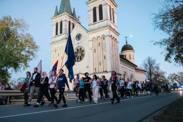 A large group of student-protestors from the southern-Serbian city of Novi Pazar march as they arrive in Novi Sad after a 16-day march to take part in a gathering marking the first anniversary of the Novi Sad railway station tragedy, in Novi Sad, on October 31, 2025. The collapse of a railway station's canopy in Serbia's second-largest city on November 1, 2024, which killed 16 people just months after renovation, became a symbol of entrenched corruption and triggered huge demonstrations, bringing hundreds of thousands to the streets under the "bloody hand" stencil that became its emblem. (Photo by UROS ARSIC / AFP)