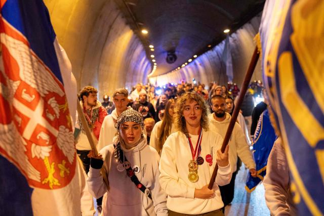 A large group of student-protestors from the southern-Serbian city of Novi Pazar wave flags as they arrive in Novi Sad after a 16-day march to take part in a gathering marking the first anniversary of the Novi Sad railway station tragedy, in Novi Sad, on October 31, 2025. The collapse of a railway station's canopy in Serbia's second-largest city on November 1, 2024, which killed 16 people just months after renovation, became a symbol of entrenched corruption and triggered huge demonstrations, bringing hundreds of thousands to the streets under the "bloody hand" stencil that became its emblem. (Photo by UROS ARSIC / AFP)