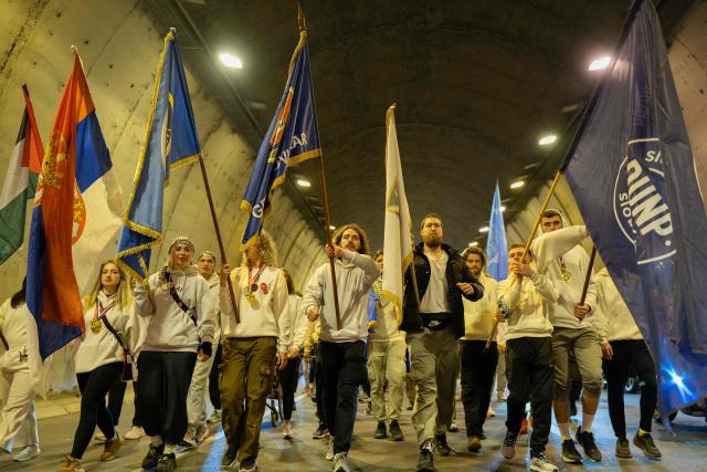 A large group of student-protestors from the southern-Serbian city of Novi Pazar wave flags as they arrive in Novi Sad after a 16-day march to take part in a gathering marking the first anniversary of the Novi Sad railway station tragedy, in Novi Sad, on October 31, 2025. The collapse of a railway station's canopy in Serbia's second-largest city on November 1, 2024, which killed 16 people just months after renovation, became a symbol of entrenched corruption and triggered huge demonstrations, bringing hundreds of thousands to the streets under the "bloody hand" stencil that became its emblem. (Photo by UROS ARSIC / AFP)