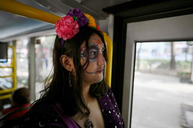 A woman with skull makeup travels on public transport ahead of the Day of the Dead celebration on Reforma Avenue in Mexico City on October 31, 2025. (Photo by Alfredo ESTRELLA / AFP)